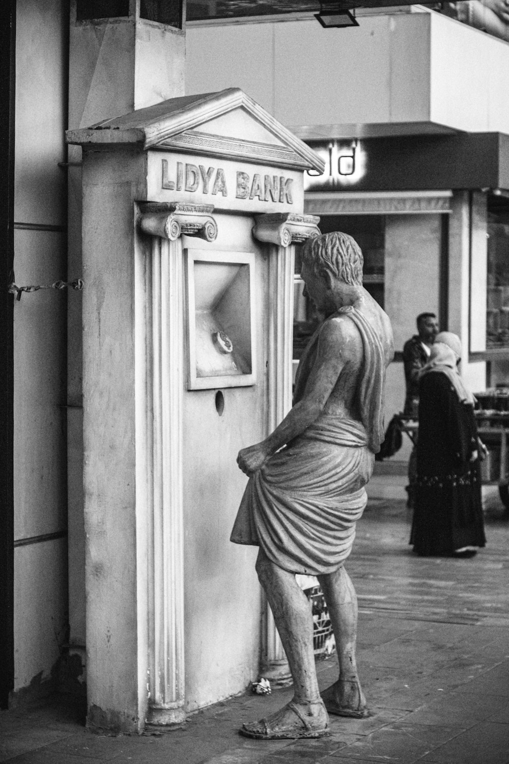 a statue of a man standing next to a atm machine