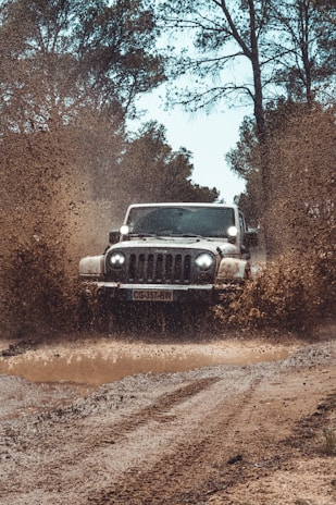 An action shot of a vehicle splashing through a muddy trail.