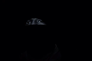 Illustration of a mysterious character cloaked in shadows, eyes glowing faintly