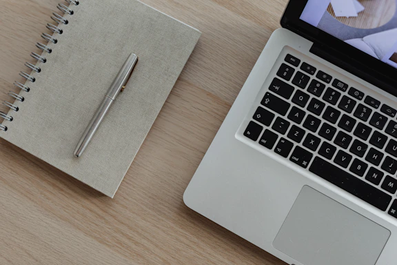 A sleek laptop on a purple velvet cloth with gold accents, next to a stylish notebook and pen.