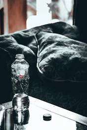 Close-up of hands adjusting a water bottle on a desk with soft brown and cream accents.