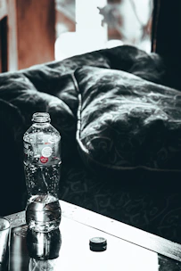 Close-up of hands adjusting a water bottle on a desk with soft brown and cream accents.