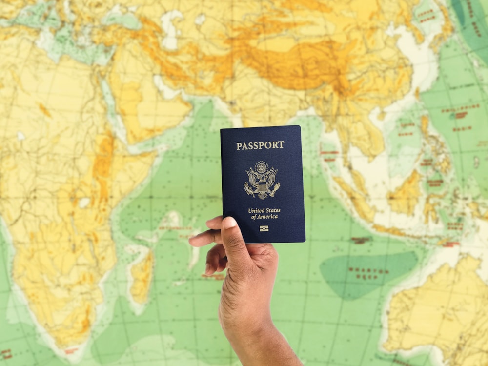 a hand holding a passport over a map