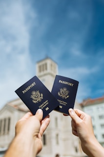 two people holding up two passports in front of a building