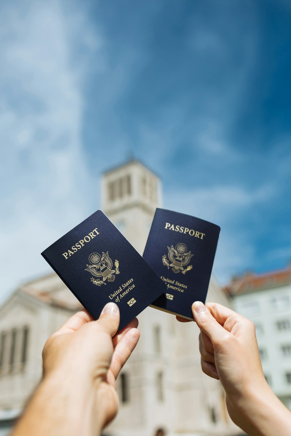 deux personnes brandissant deux passeports devant un immeuble