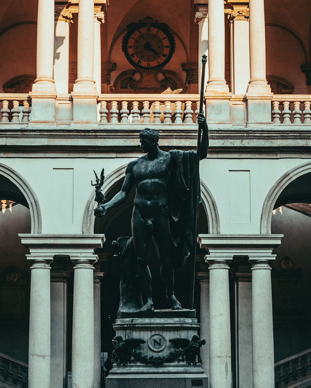 a statue of a man holding a sword in front of a building