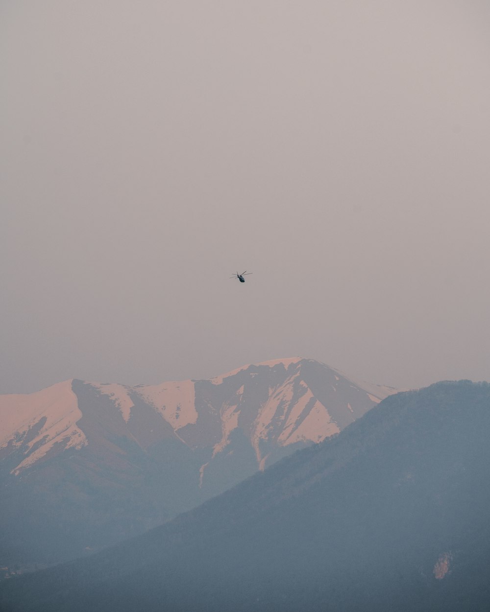 a bird flying in the sky over a mountain range