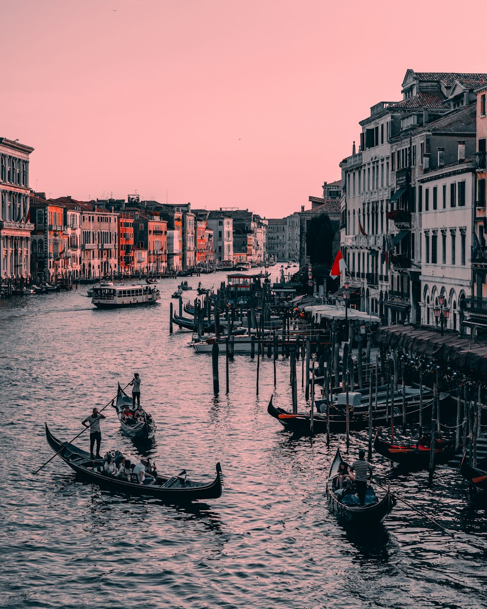 a couple of boats floating down a river next to tall buildings