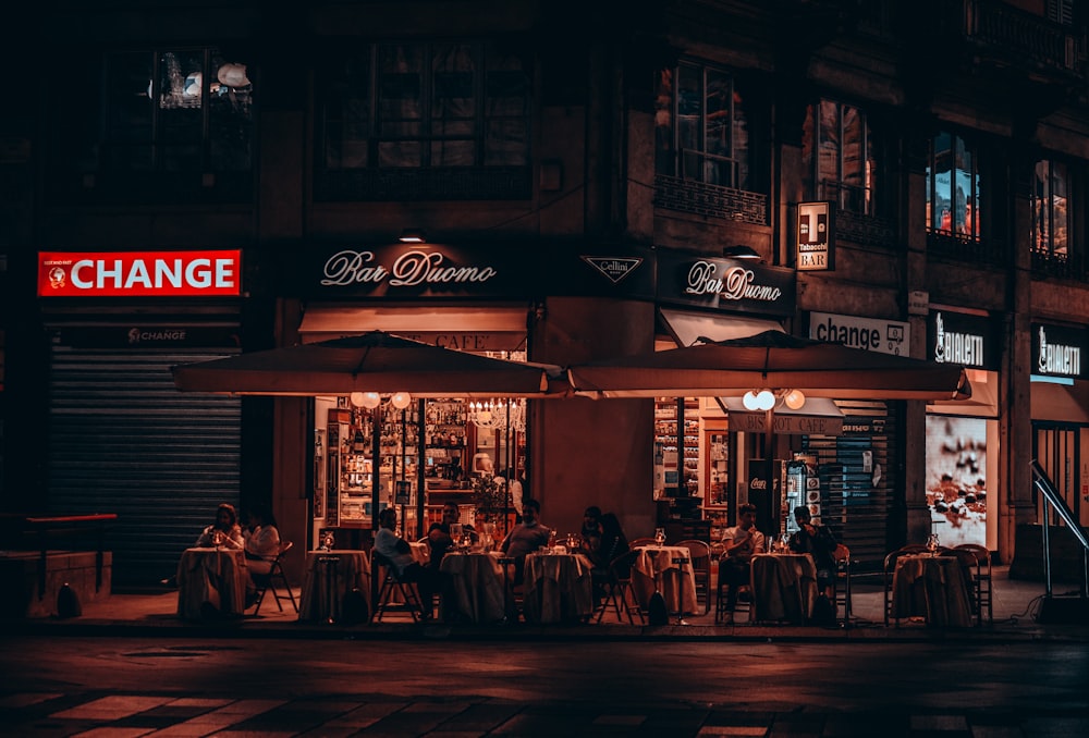 a group of people sitting at a table outside of a restaurant