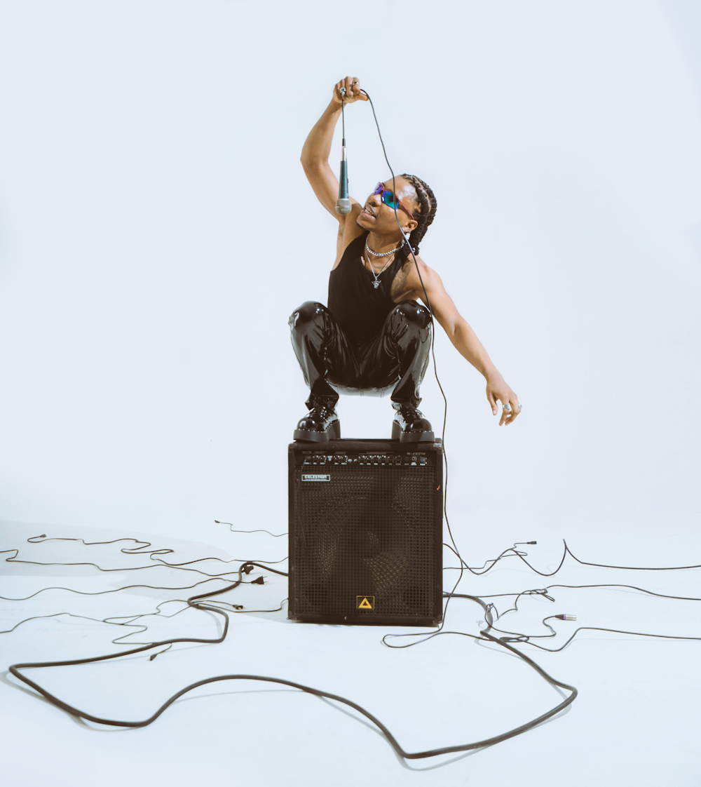 a woman in a black top is sitting on top of a amp