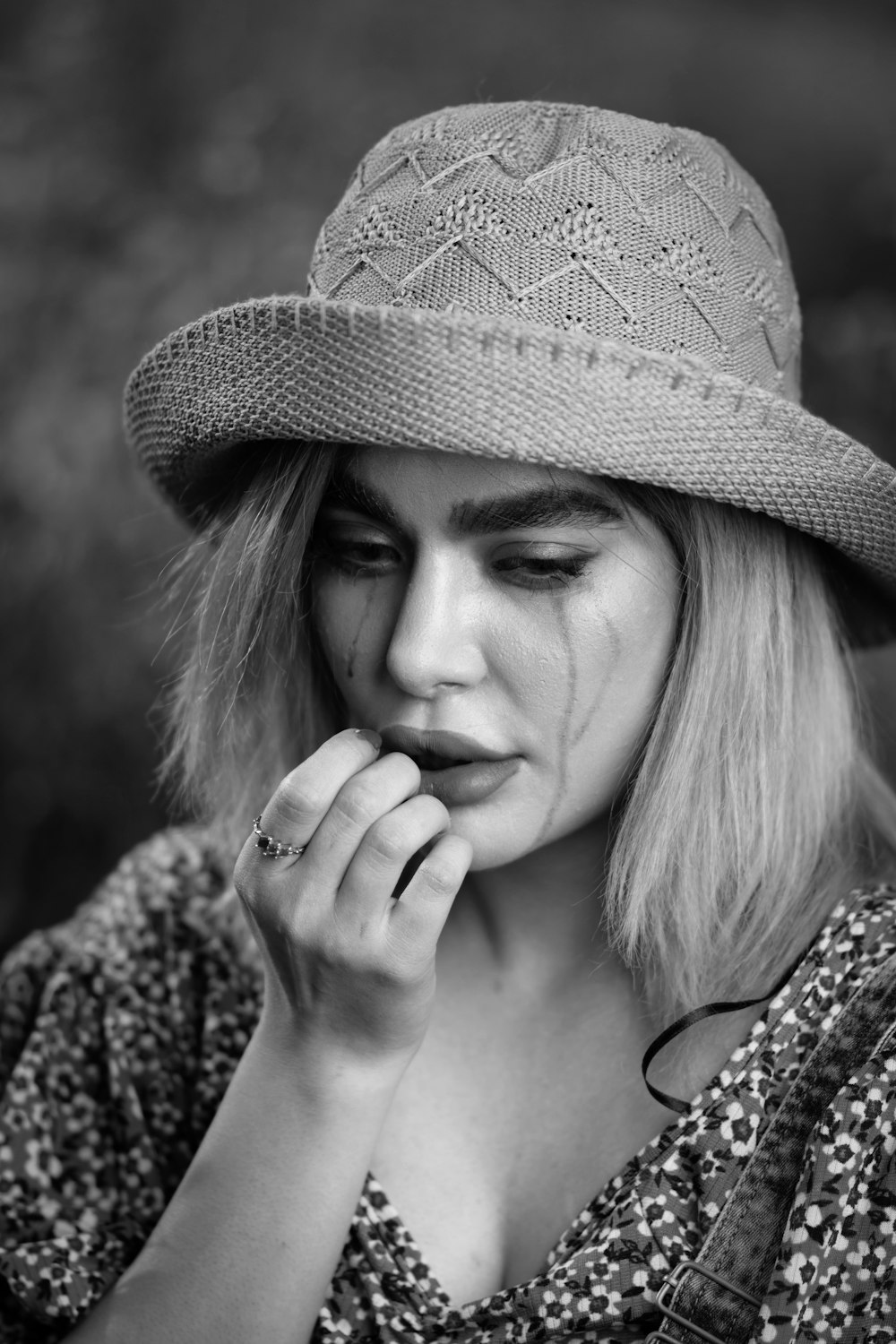 a woman wearing a hat and holding her hand to her mouth