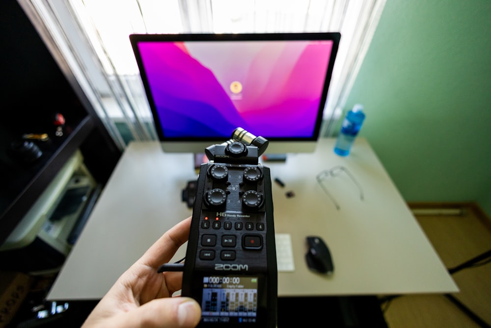 a person holding a remote control in front of a computer
