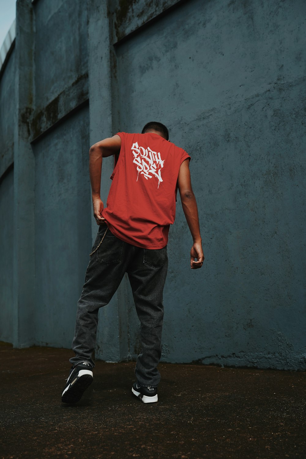 a man in a red shirt is doing a trick on a skateboard