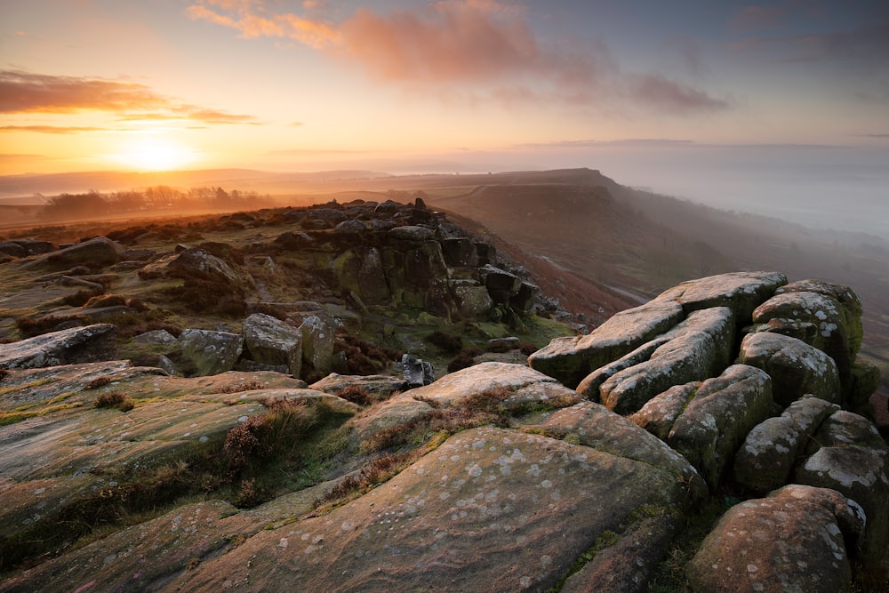 the sun is setting over a rocky landscape