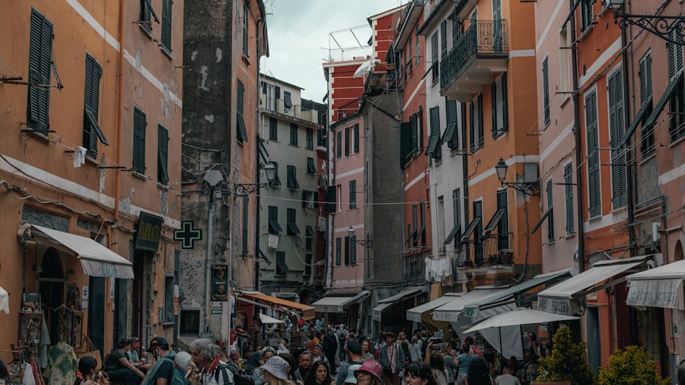 a group of people walking down a street next to tall buildings