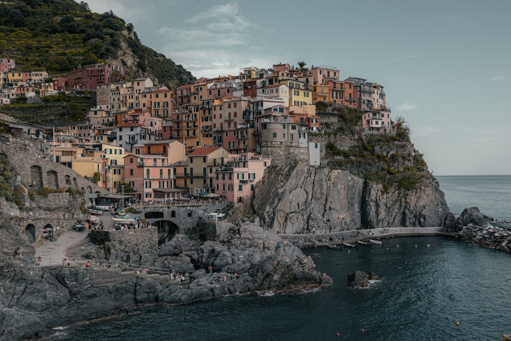 a group of buildings on the side of a cliff next to a body of water