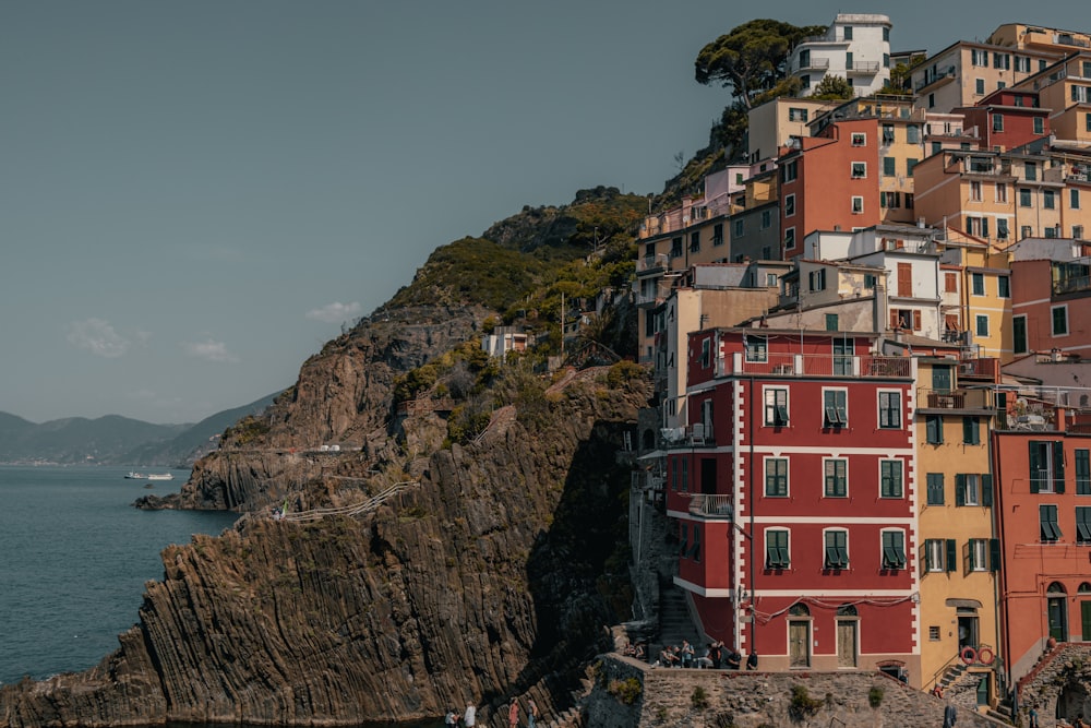 a group of buildings sitting on top of a cliff next to a body of water