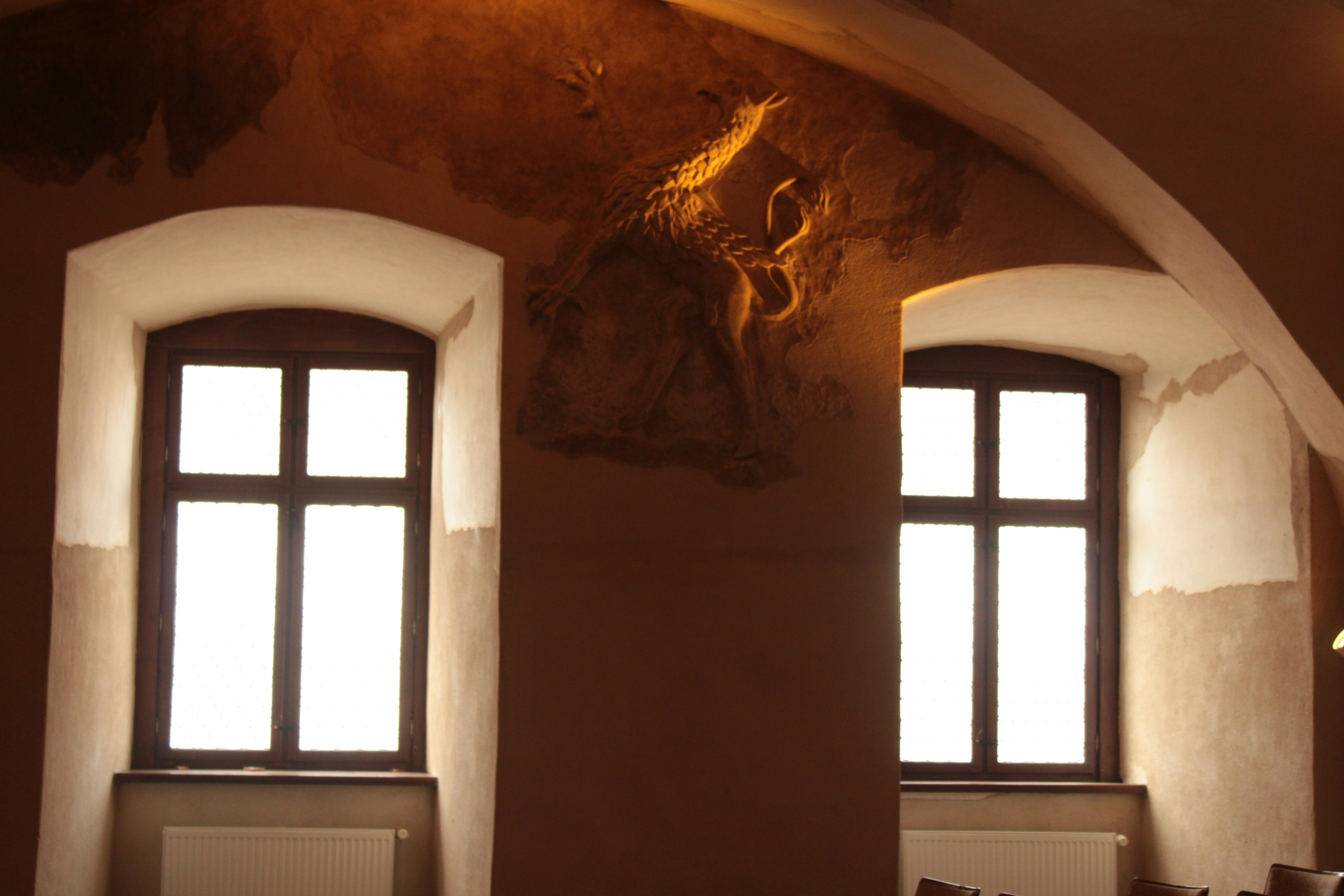 une pièce avec deux fenêtres et une sculpture sur le mur