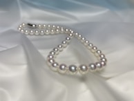 Artistic arrangement of pearl strands cascading over a polished gold surface, highlighting luxury craftsmanship.