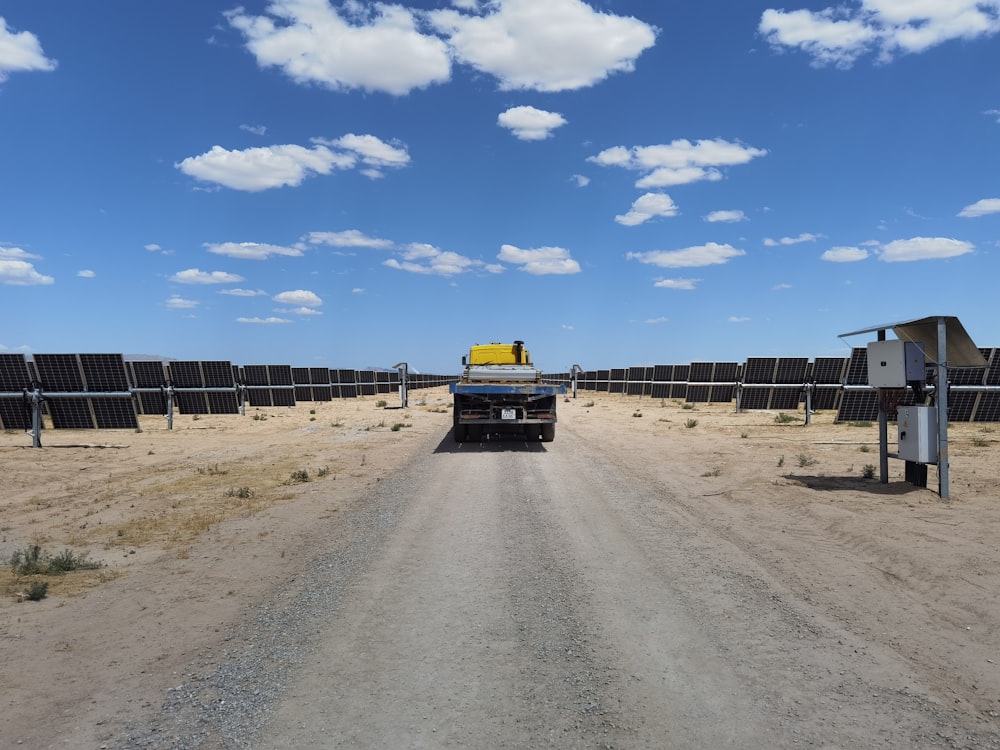 a truck driving down a dirt road next to solar panels