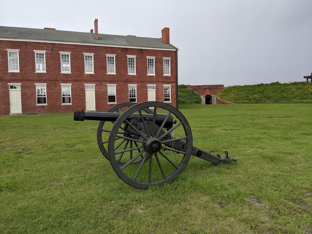 a large brick building with a cannon in front of it