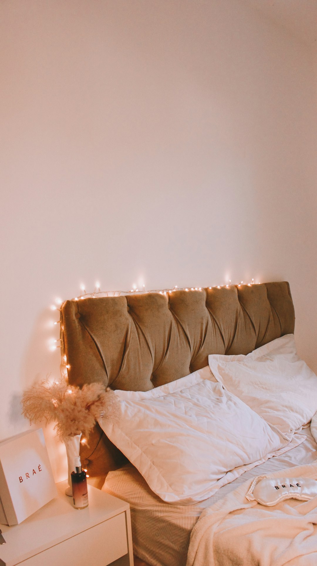 Tufted headboard with warm fairy lights and soft bedding