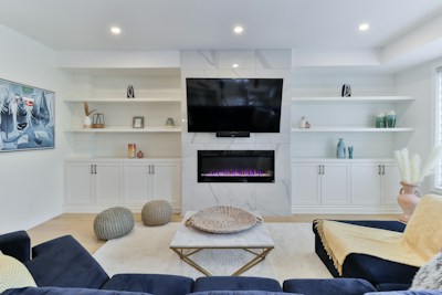 Custom Entertainment Center with Fireplace - Stunning built-in entertainment wall with stone fireplace feature by Sage Kitchen and Bath in Storage & Organization