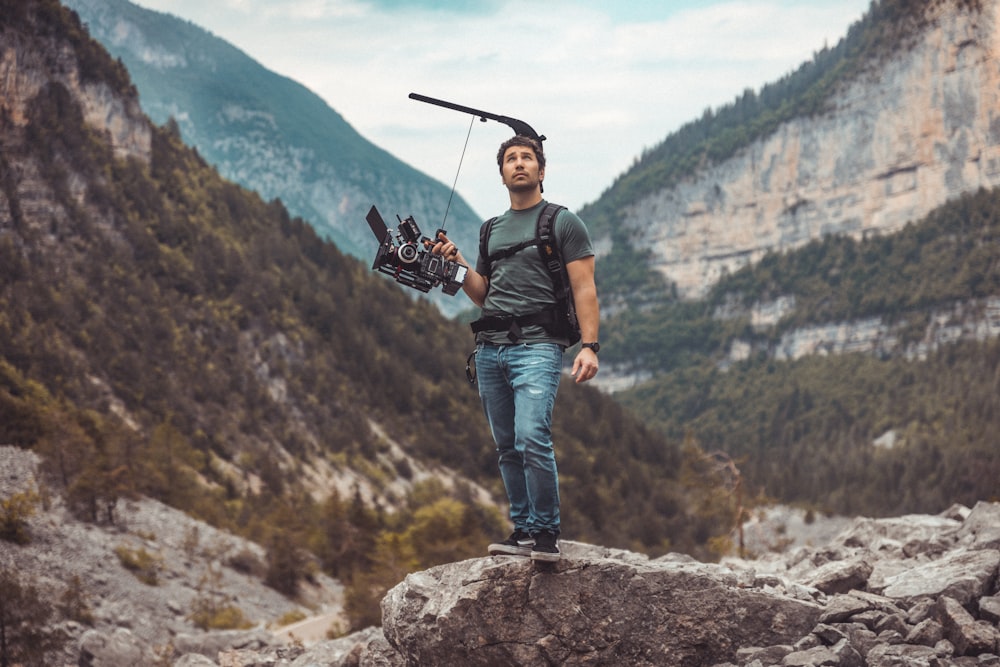 a man holding a pair of skis on top of a mountain