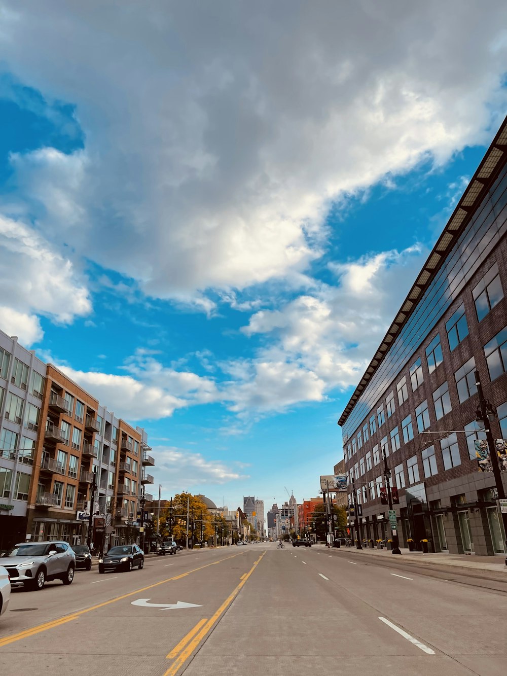 a city street lined with tall buildings under a cloudy blue sky