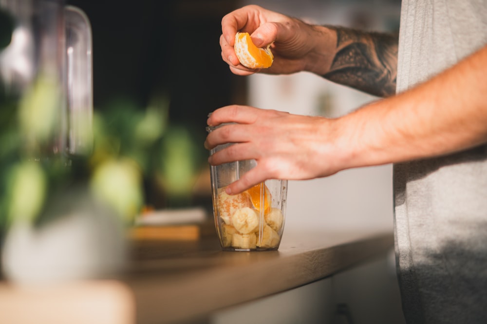 a person holding an orange in a jar