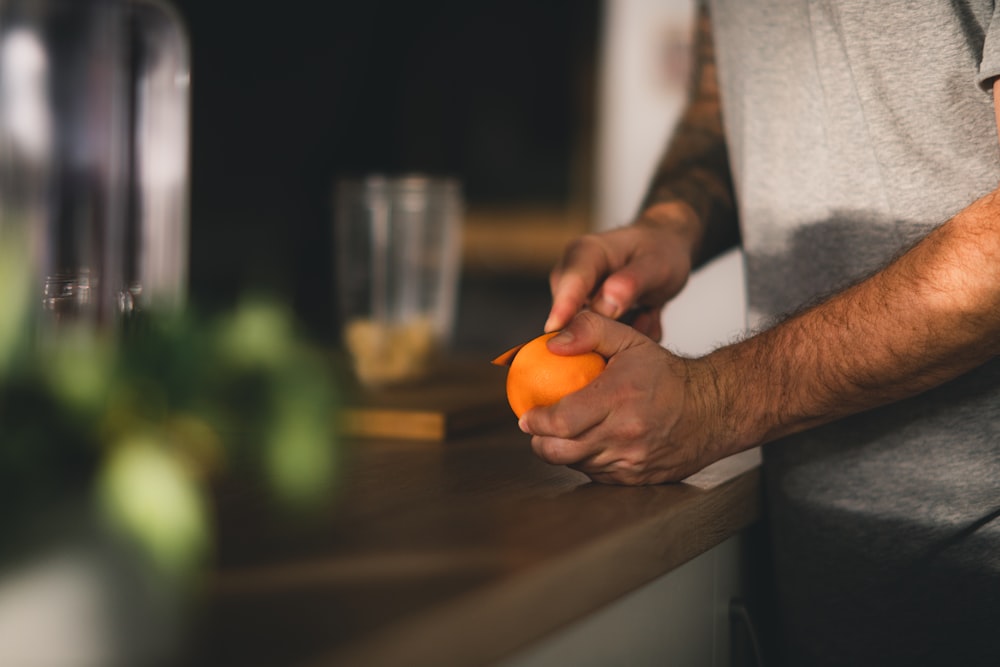 a man is peeling an orange on a counter