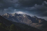 Wide shot of a mountain range under dramatic cloudy skies.