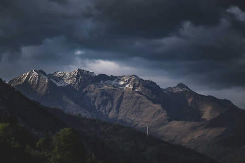 Wide shot of a mountain range under dramatic cloudy skies.