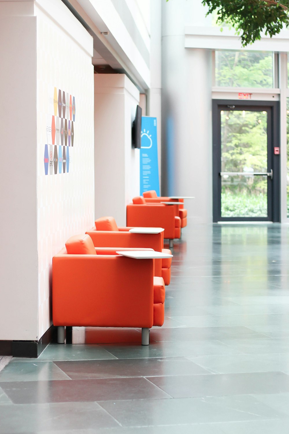 a row of orange chairs sitting next to a white wall