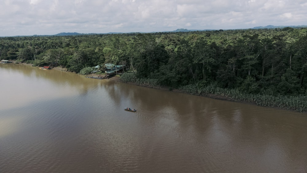 a boat floating on top of a lake surrounded by forest