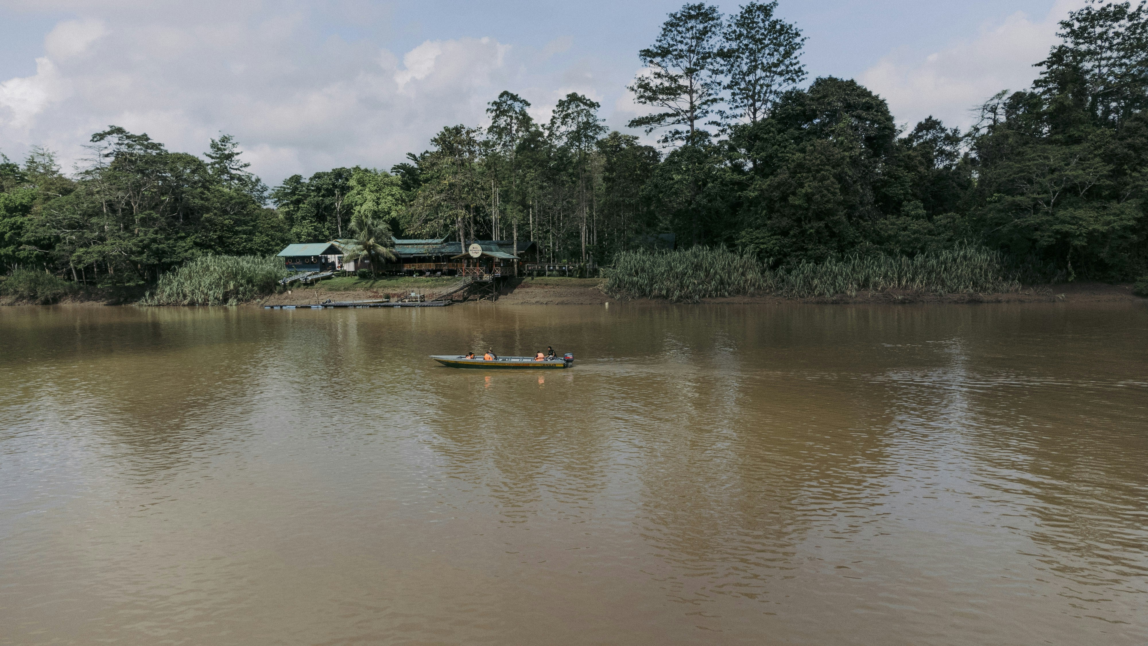 a boat floating on top of a lake next to a forest