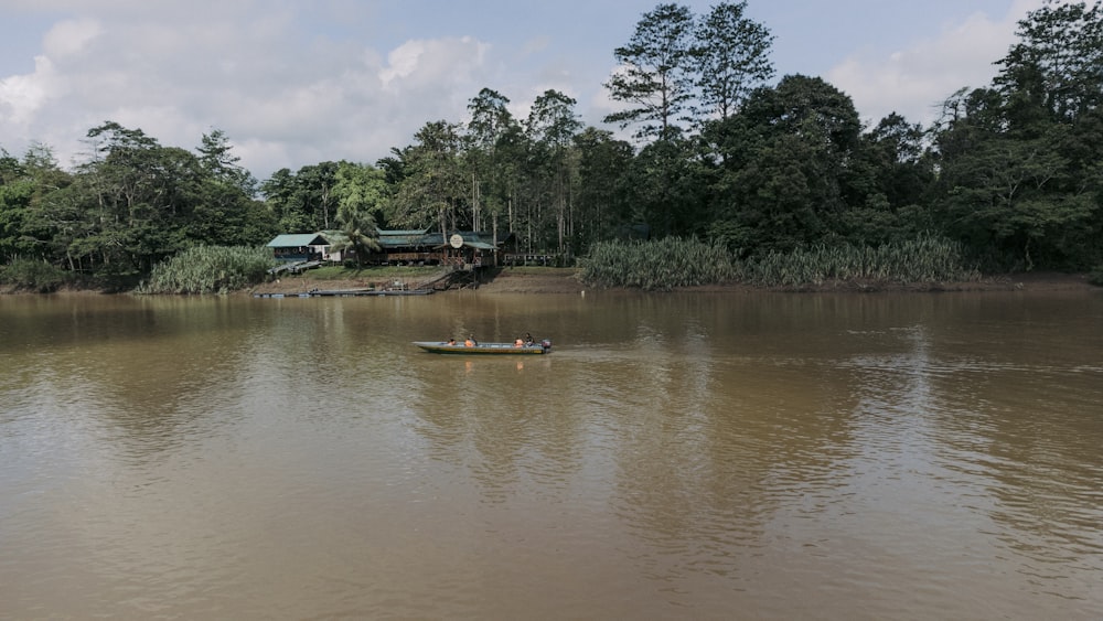 a boat floating on top of a lake next to a forest