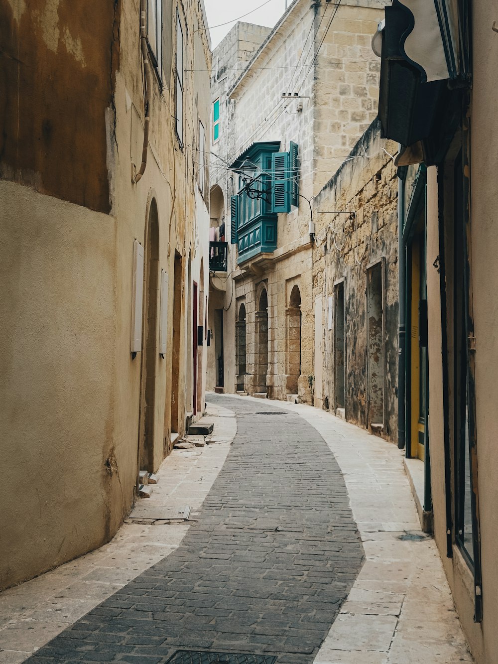 a narrow street with a cobblestone walkway between two buildings