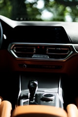 A modern car interior featuring a sleek dashboard with digital displays and a central console. The design has a luxurious feel with leather upholstery and chrome accents. The gear shifter and control dial are prominently positioned.