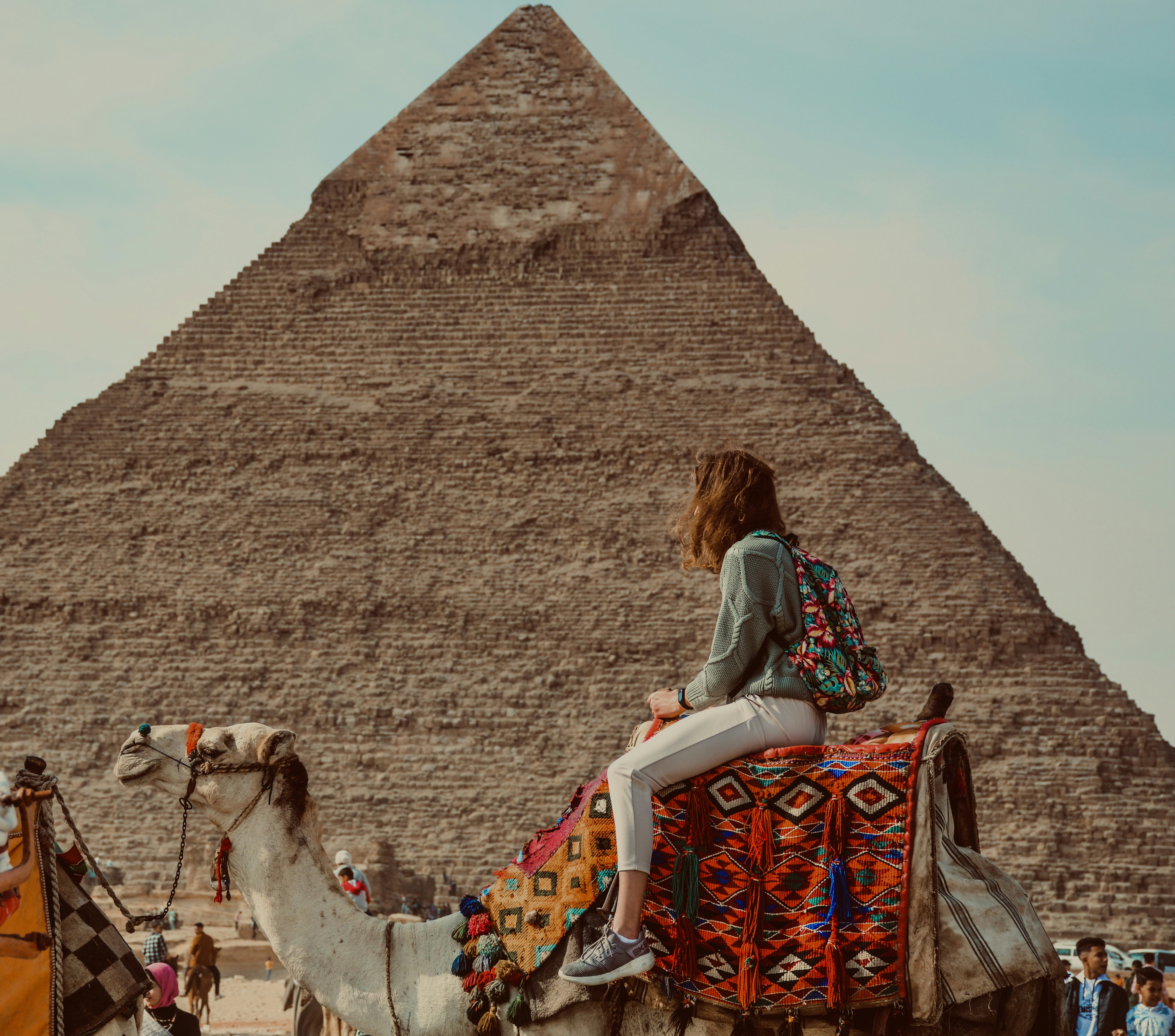 A woman sitting on top of a camel in front of a pyramid