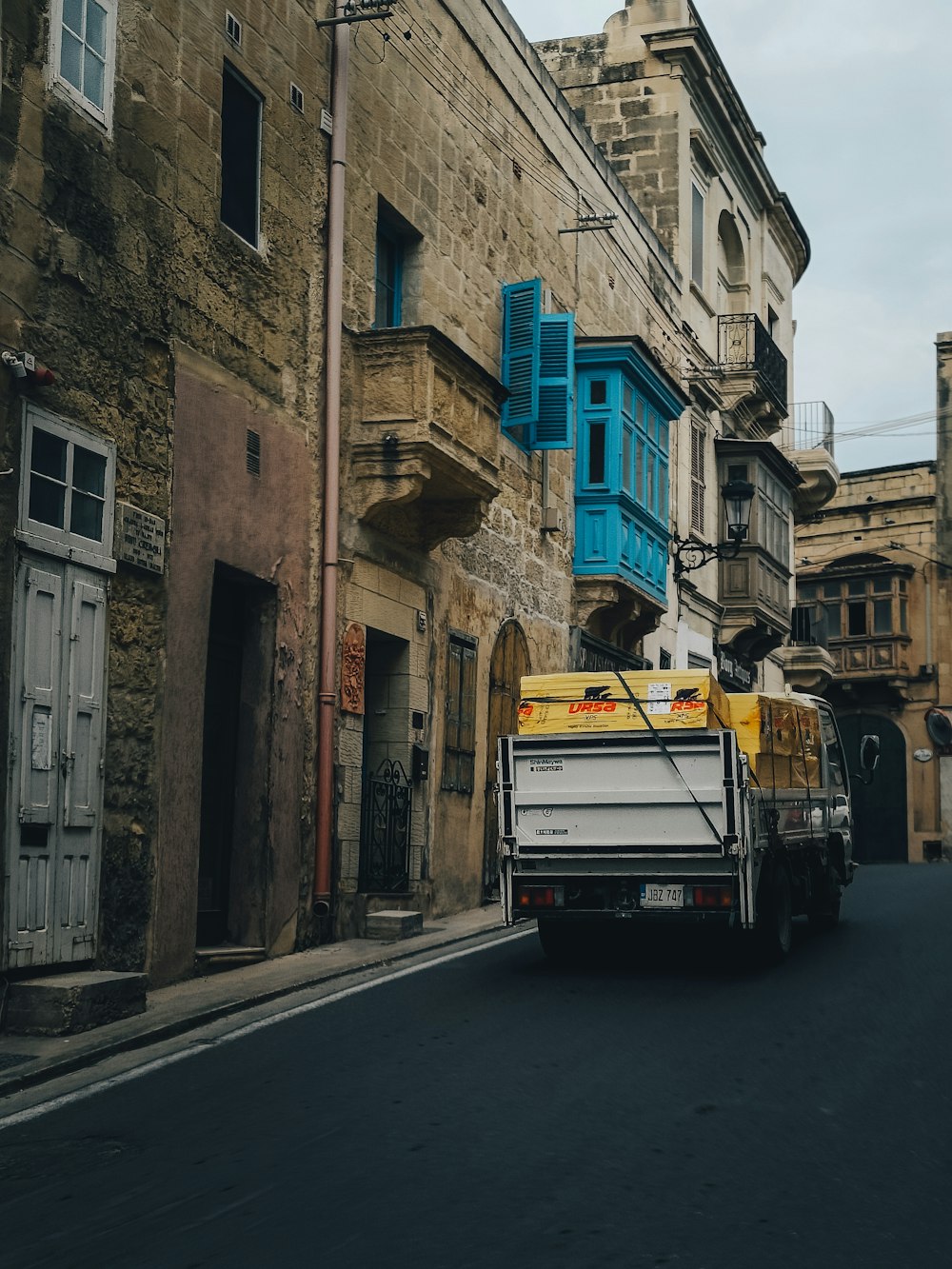 a truck driving down a street next to tall buildings