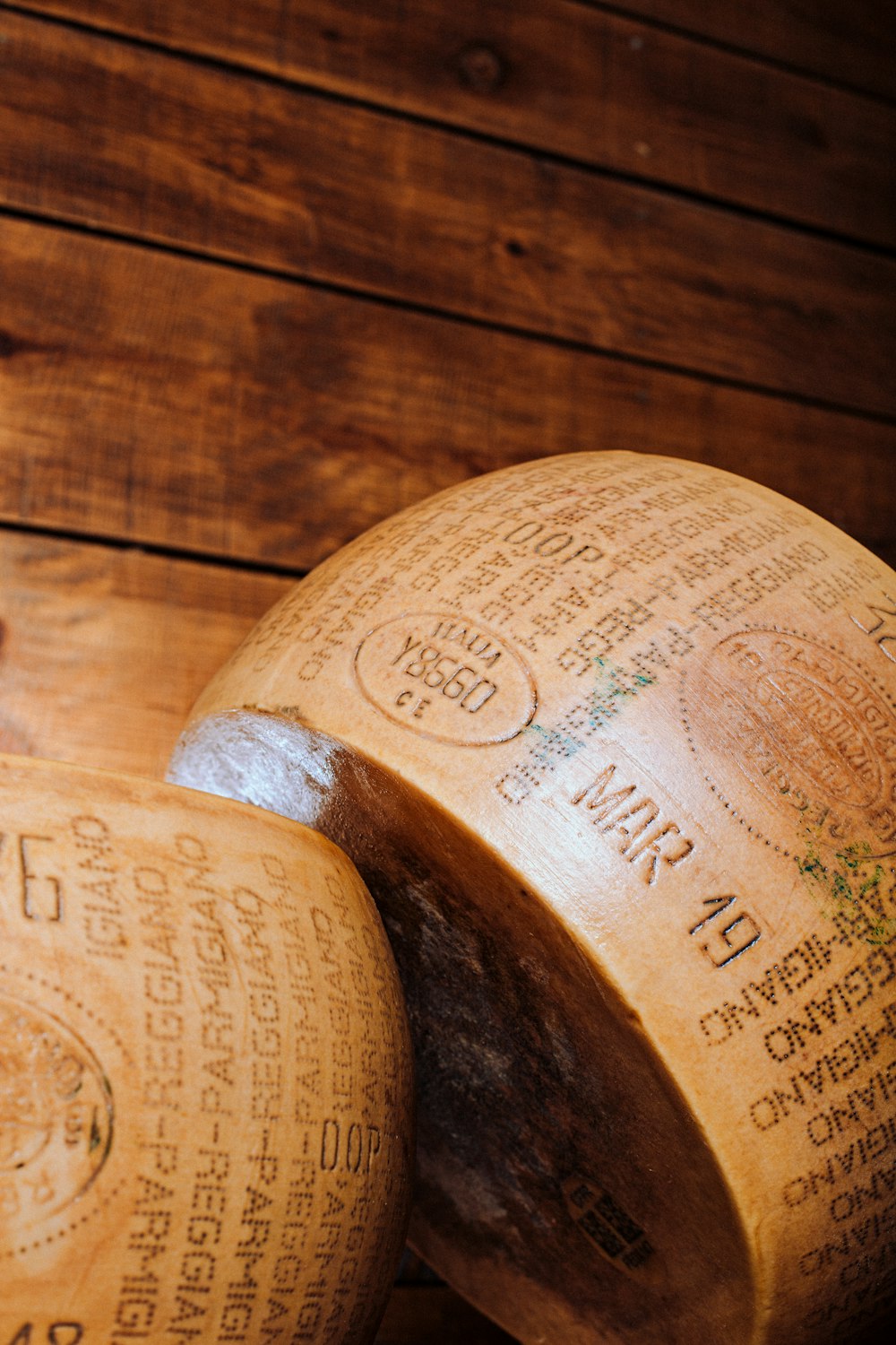 a close up of two cheese wheels on a wooden surface