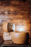 Close-up of Parmigiano Reggiano cheese wheels aging in a traditional cellar.