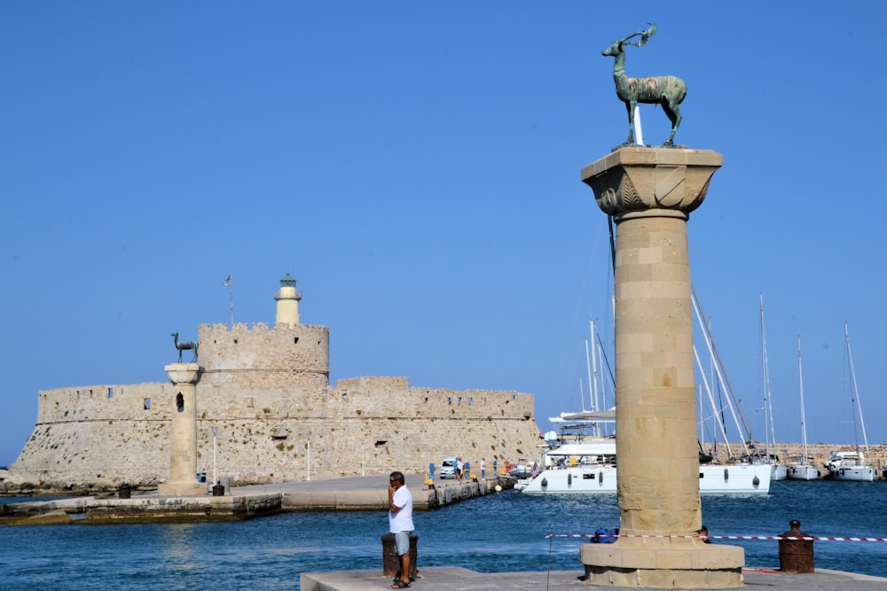 a man standing next to a statue near a body of water