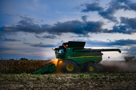 Wide shot of a green John Deere machine harvesting cotton at dawn