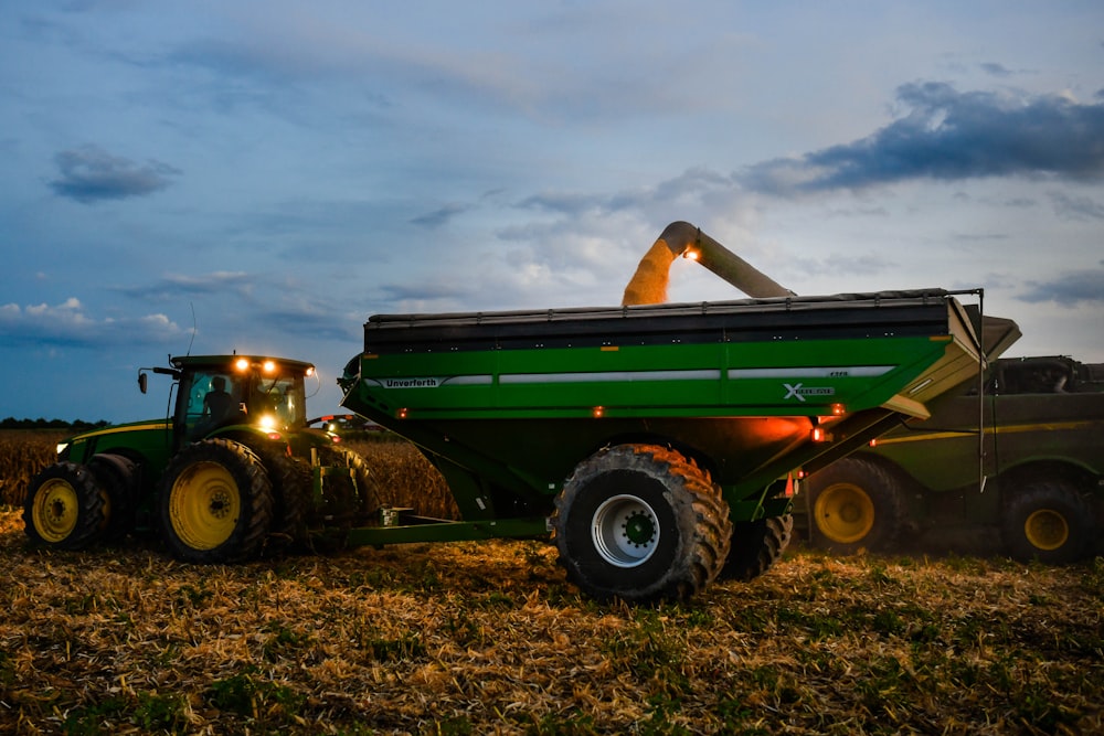 a large green tractor with lights on in a field