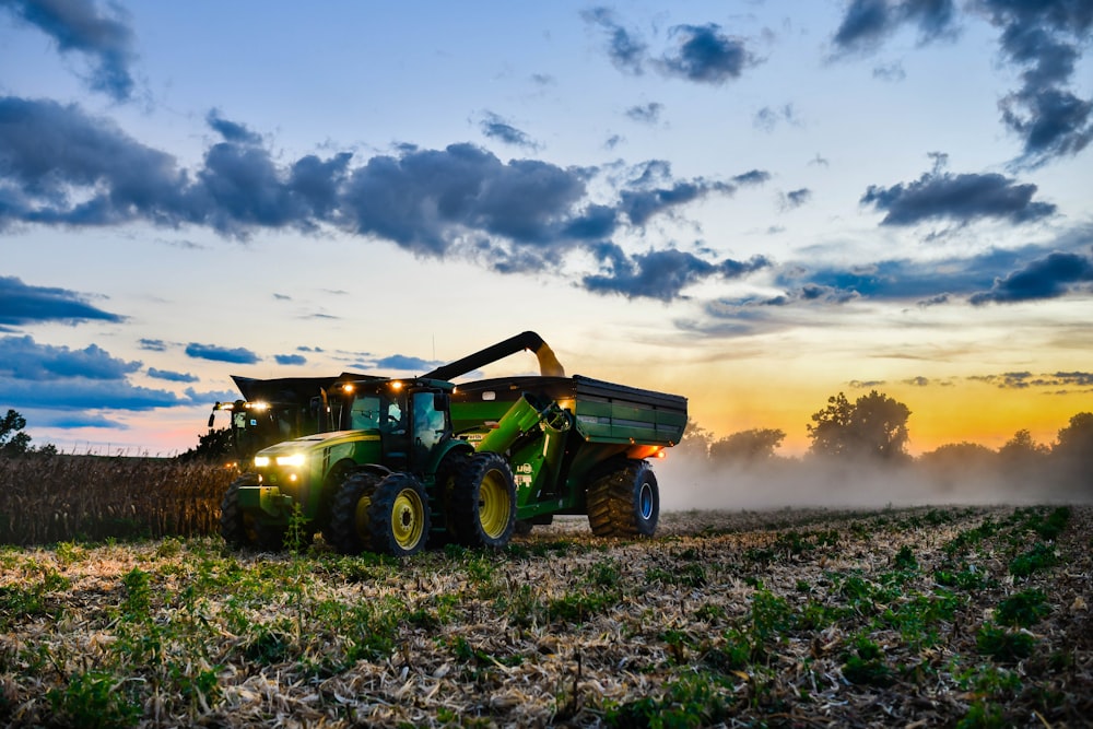 a tractor is driving through a field at sunset