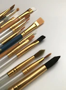 Close-up of various professional paintbrushes and rollers laid out on a wooden table.