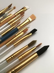 A selection of fine paintbrushes with colorful bristles resting on a canvas.