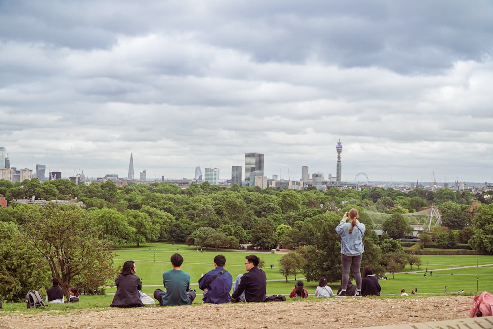 a group of people sitting on top of a lush green field